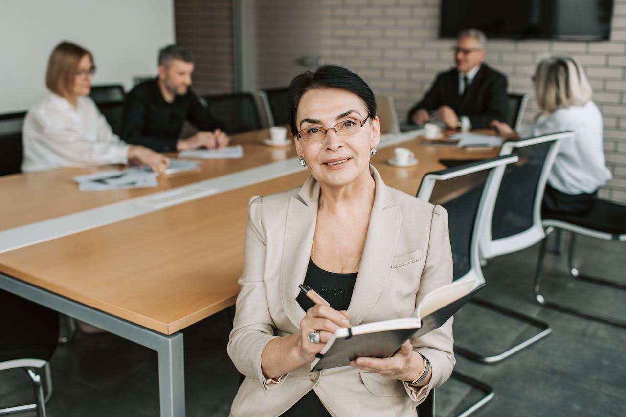 services-04 Senior businesswoman leading a meeting with colleagues in a modern office space.